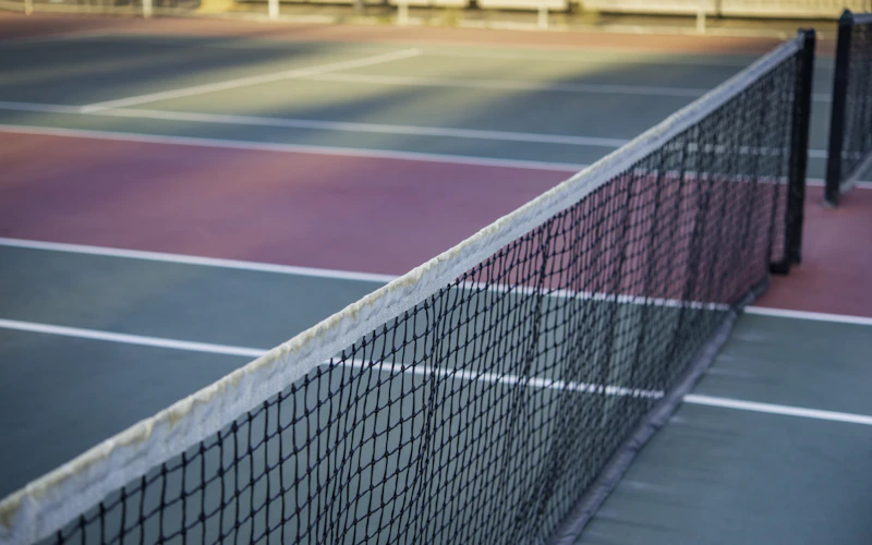 A smartwatch-style fitness tracker beside tennis gear, representing wearable recovery technology in tennis